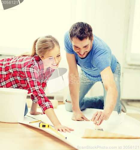 Image of smiling couple smearing wallpaper with glue