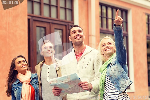 Image of group of smiling friends with map exploring city