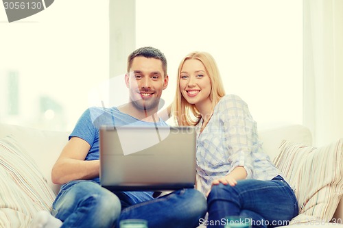 Image of smiling happy couple with laptop at home