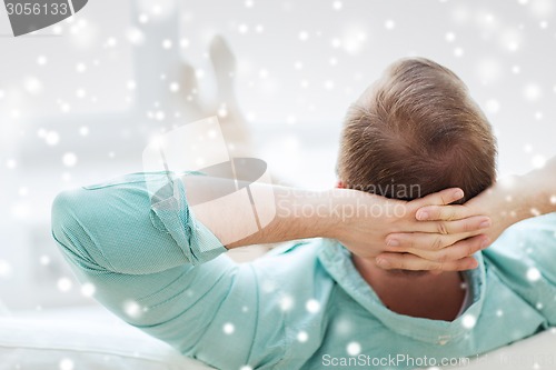 Image of man lying or sitting on sofa at home from back