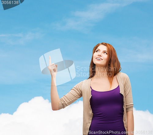 Image of smiling teenage girl pointing finger up