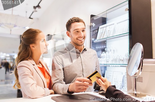 Image of happy couple choosing engagement ring in mall