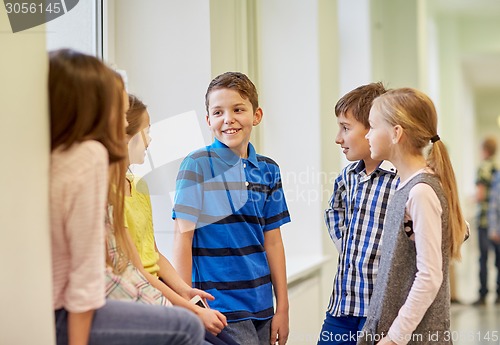 Image of group of smiling school kids talking in corridor