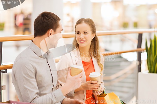 Image of happy couple with shopping bags drinking coffee