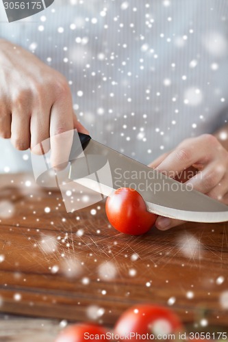 Image of close up of man cutting tomato on board with knife