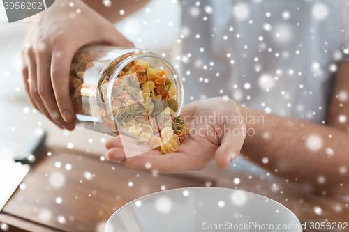 Image of close up of man emptying jar with colorful pasta