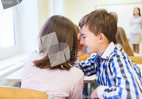 Image of smiling schoolgirl whispering to classmate ear