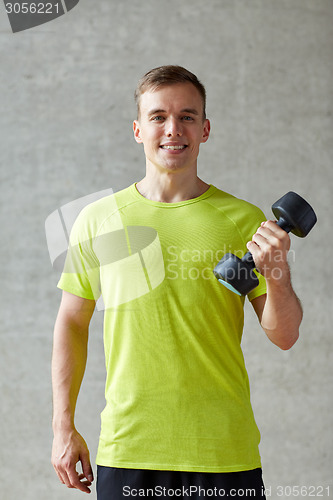 Image of smiling man with dumbbell in gym