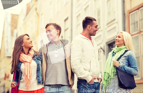 Image of group of smiling friends walking in the city