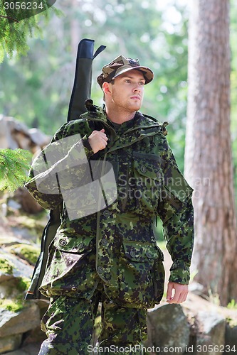 Image of young soldier or hunter with gun in forest