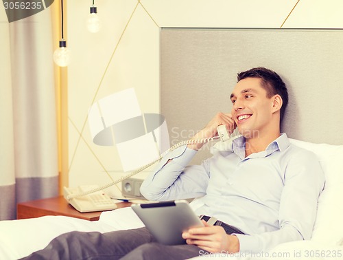 Image of businessman with tablet pc and phone in hotel room