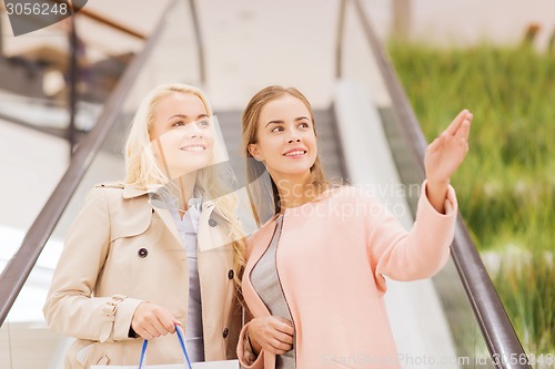 Image of young women pointing finger on escalator in mall