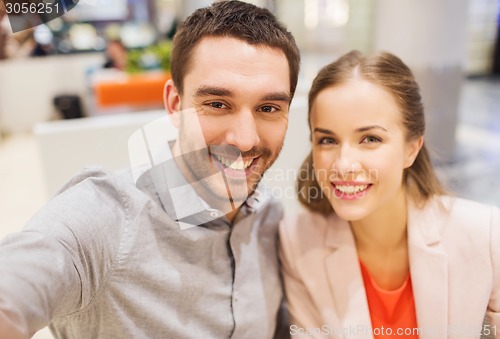 Image of happy couple taking selfie in mall or office