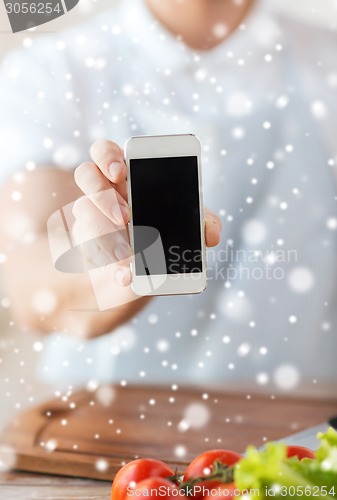 Image of closeup of man showing smartphone in kitchen