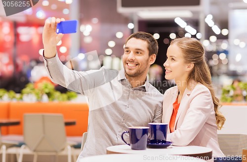 Image of happy couple with smartphone taking selfie in mall