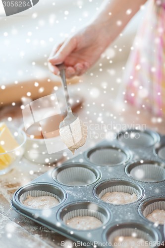 Image of close up of woman filling muffins molds with dough