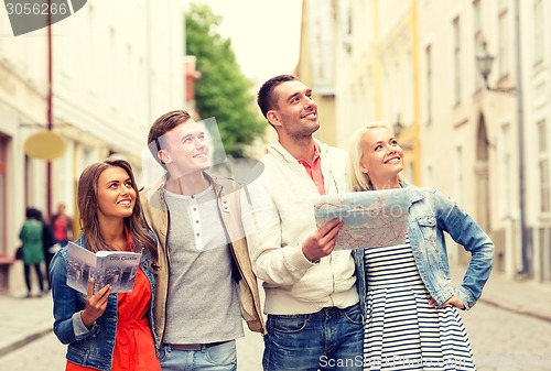 Image of group of smiling friends with city guide and map