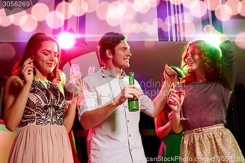 Image of smiling friends with wine glasses and beer in club