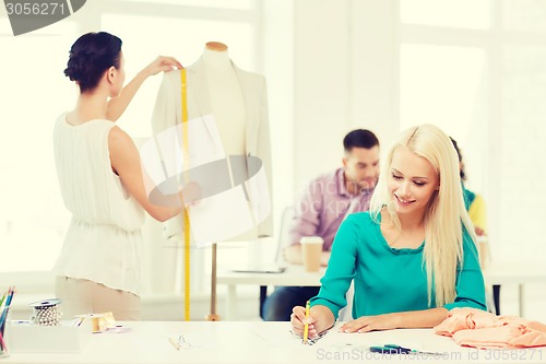 Image of smiling fashion designers working in office