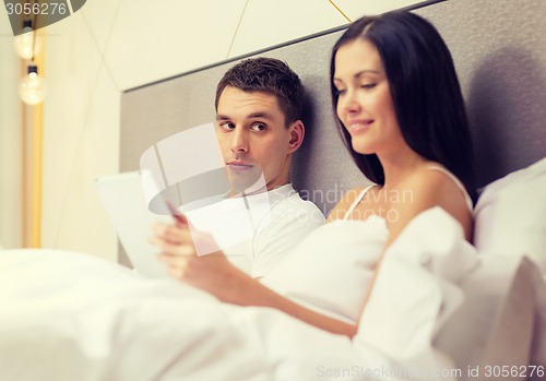 Image of smiling couple in bed with tablet pc computers