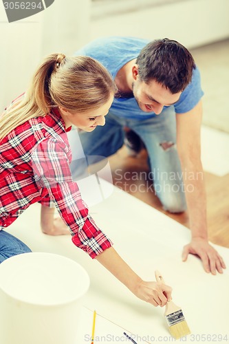 Image of smiling couple smearing wallpaper with glue