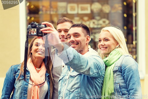 Image of group of smiling friends making selfie outdoors