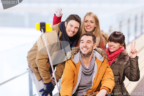 Image of happy friends with smartphone on skating rink