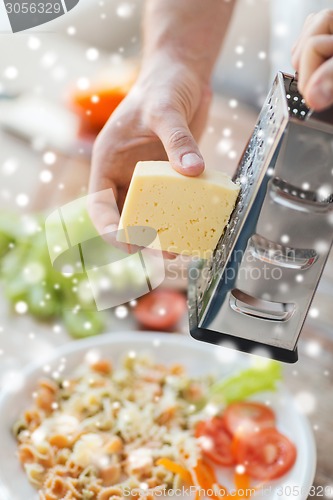 Image of close up of male hands with grater grating cheese