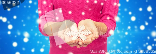 Image of close up of woman in sweater holding snowflake