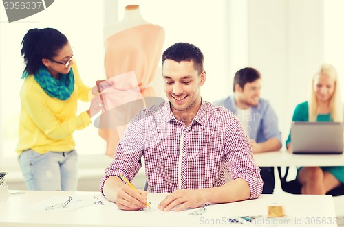 Image of smiling fashion designers working in office