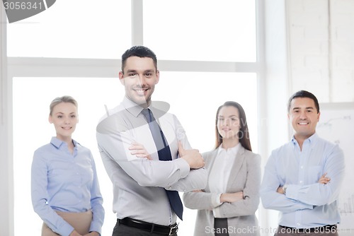 Image of smiling businessman in office with team on back