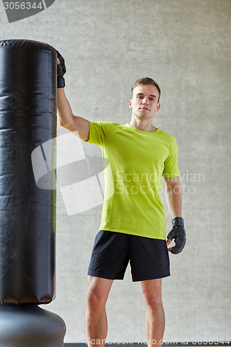 Image of man with boxing gloves and punching bag in gym