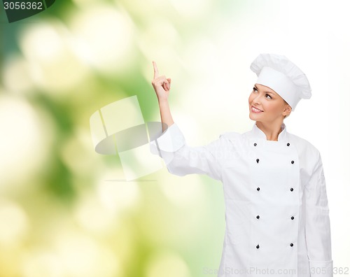 Image of smiling female chef pointing finger to something