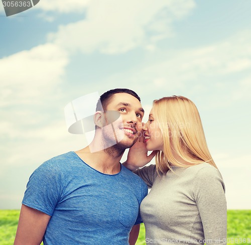 Image of smiling girlfriend telling boyfriend secret