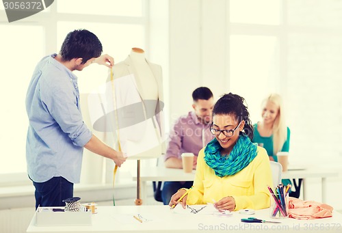 Image of smiling fashion designers working in office