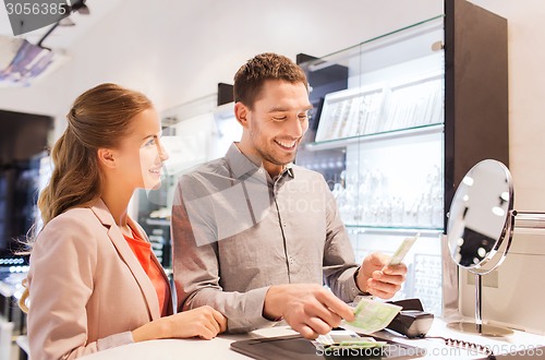 Image of happy couple paying for purchase in store