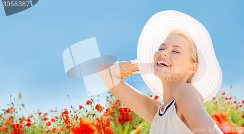 Image of smiling young woman in straw hat on poppy field