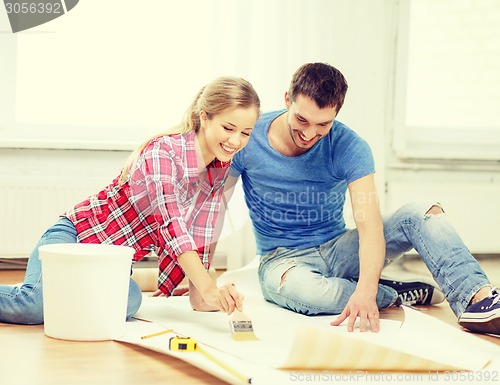 Image of smiling couple smearing wallpaper with glue