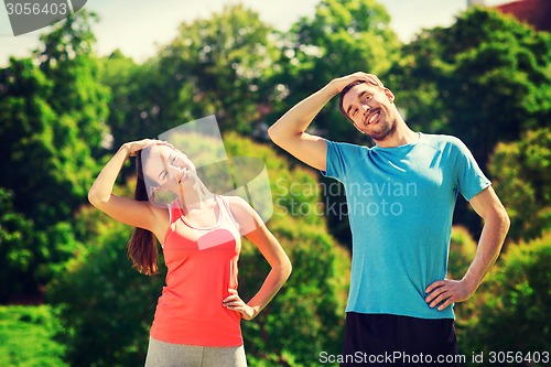 Image of smiling couple stretching outdoors