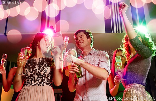 Image of smiling friends with wine glasses and beer in club