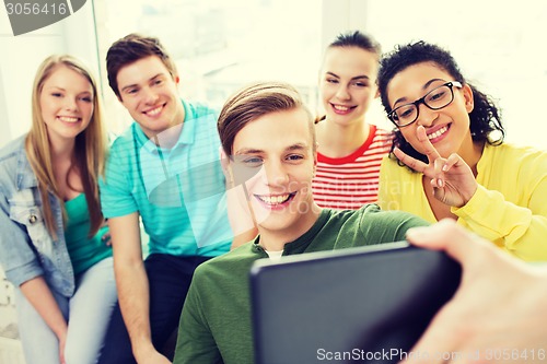 Image of smiling students making picture with tablet pc