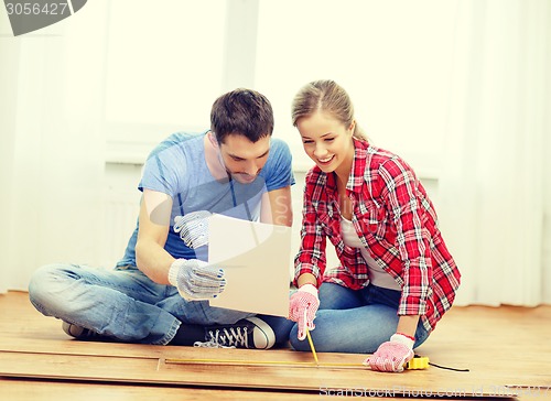 Image of smiling couple measuring wood flooring