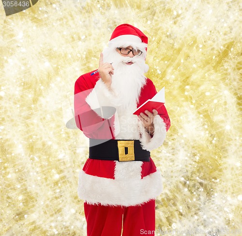 Image of man in costume of santa claus with notepad