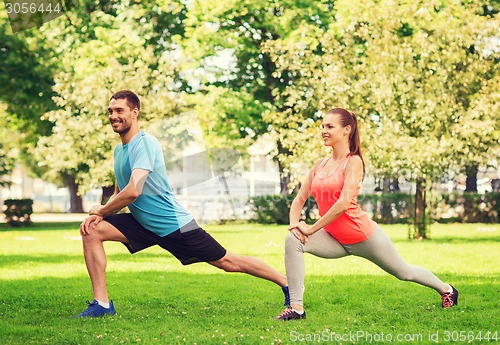 Image of smiling couple stretching outdoors