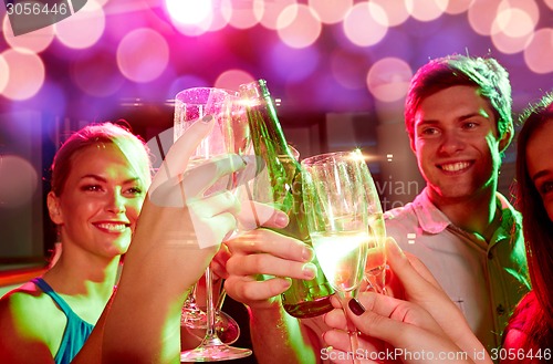 Image of smiling friends with wine glasses and beer in club