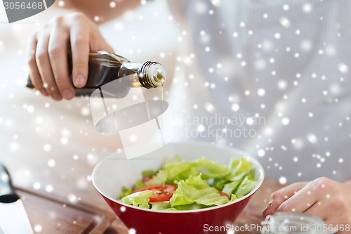 Image of close up of hands flavoring salad with olive oil