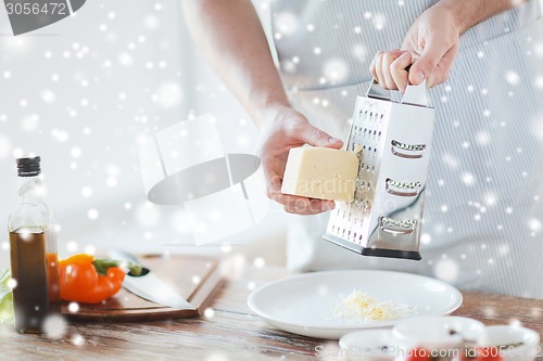 Image of close up of male hands with grater grating cheese