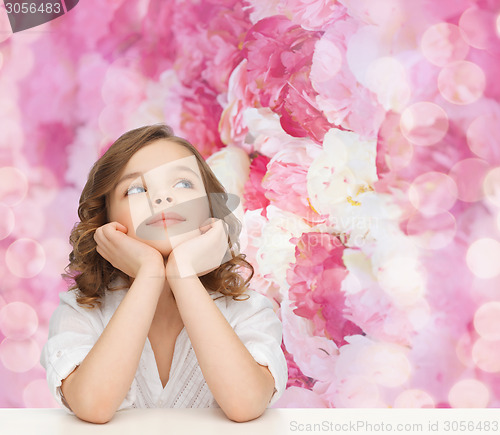 Image of beautiful girl sitting at table and looking up
