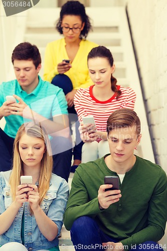 Image of busy students with smartphones sitting on stairs