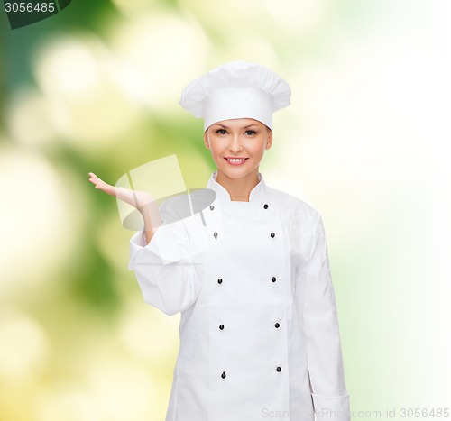 Image of smiling female chef holding something on hand